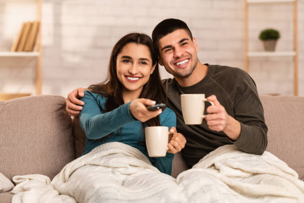 couple sitting on couch and watching tv - apartment television family couple imagens e fotografias de stock