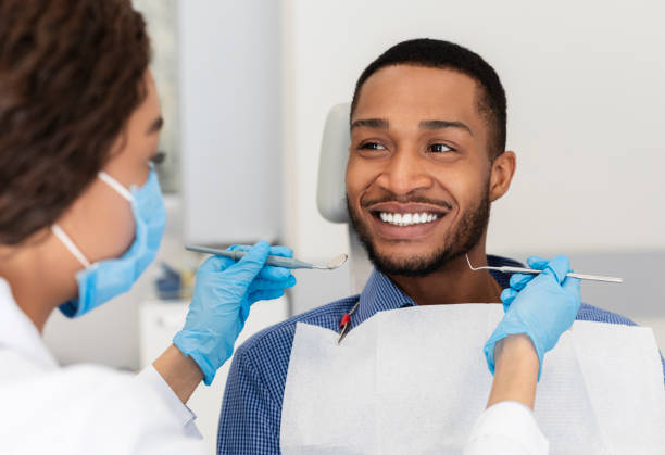 hombre sonriente en la silla del dentista mirando con confianza al médico - dental drill fotografías e imágenes de stock