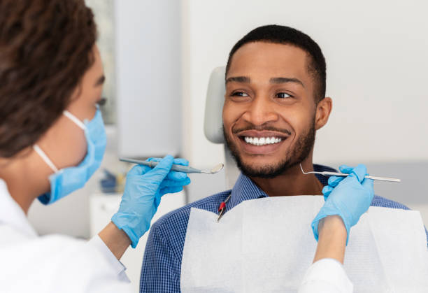 dişçi koltuğunda gülümseyen adam doktora güvenle bakıyor - diş sağlığı lar stok fotoğraflar ve resimler