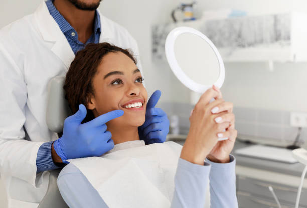 dame attirante vérifiant son beau sourire dans le miroir - dental assistent photos et images de collection