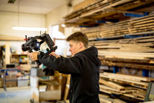 young man films in carpentry shop - movie location imagens e fotografias de stock