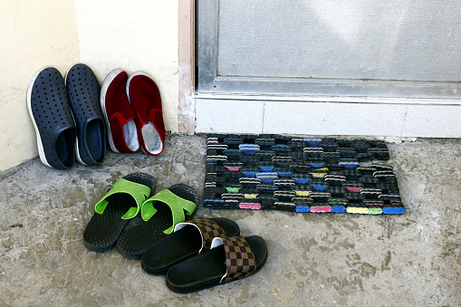Photo of shoes and slippers on the doorway of a house.