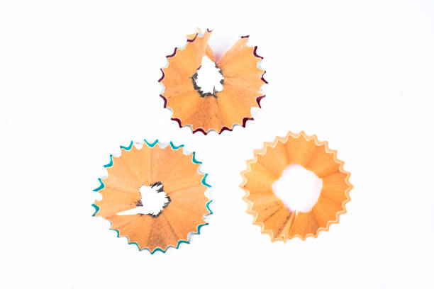 Three circle shaped wood pencil shavings placed in a triangle shape on a white isolated background