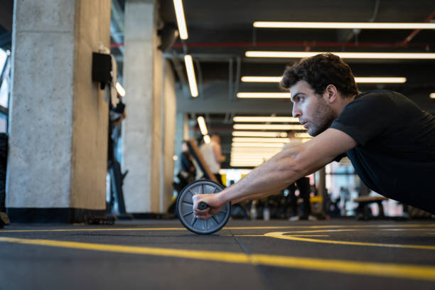 istock Side view of a man working out at the gym using an ab wheel 1222244333