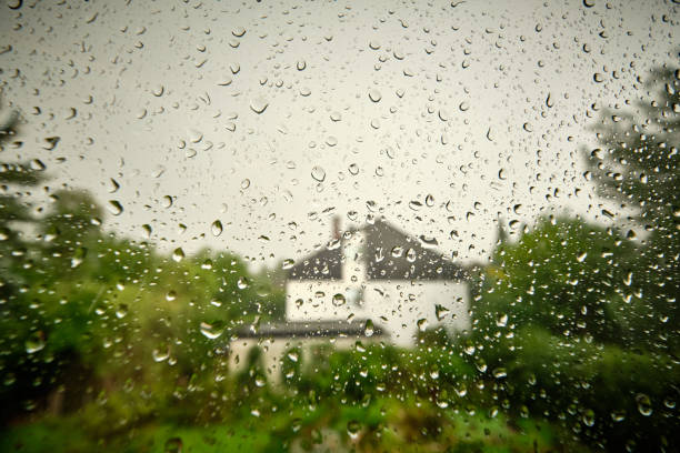 View on garden and house through window with rain drops stock photo
