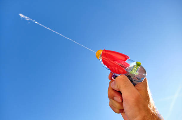 Colorful water pistol in man's hand against blue sky stock photo