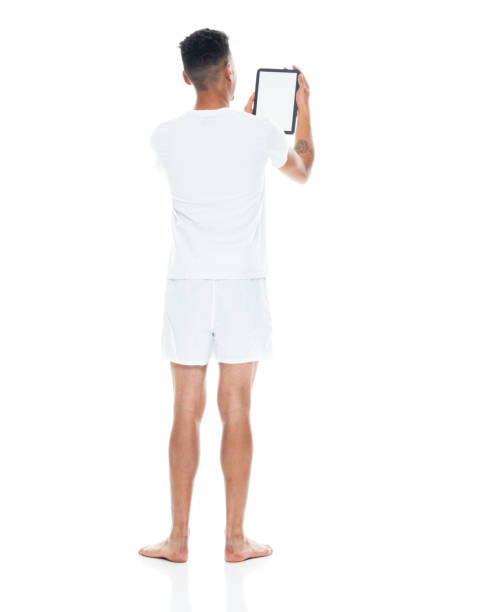 下着を着てタッチスクリーンを使用して白い背景の前に立っているアフリカ系アメリカ人の民族若い男性 - underwear men t shirt white ストックフォトと画像