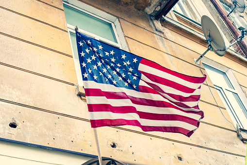 USA flag waving on old house background, vintage style photo
