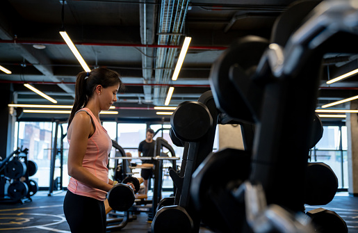 Portrait of a strong woman working out at the gym using free-weights â active lifestyle concepts