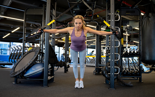 Athletic woman doing suspension training with ropes at the gym â fitness concepts