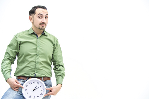 Time concept. Crazy bearded man in green shirt with funny face expression, holding clock, isolated on white background.