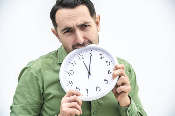 istock Totally exhausted man biting an alarm clock on a white background. 1222251084