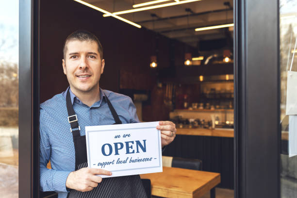 Reopening of a small business activity after the covid-19 lockdown quarantine Small business owner smiling while holding open sign of restaurant reopening after lockdown quarantine due to coronavirus pandemic - Entrepeneur opening cafeteria activity to support local businesses. reopening photos stock pictures, royalty-free photos & images