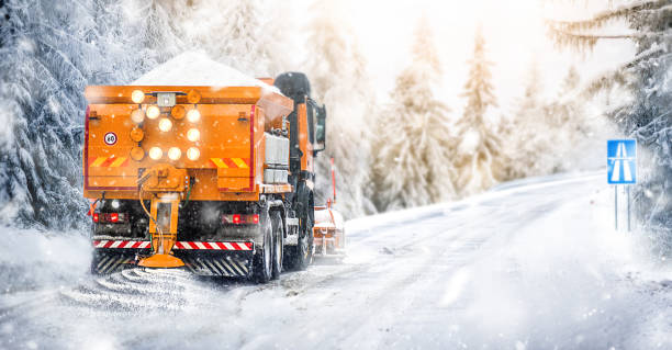 Salting highway maintenance. Snow plow truck on snowy road in action. stock photo