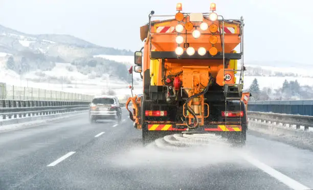 Photo of Snow plow on highway salting road.