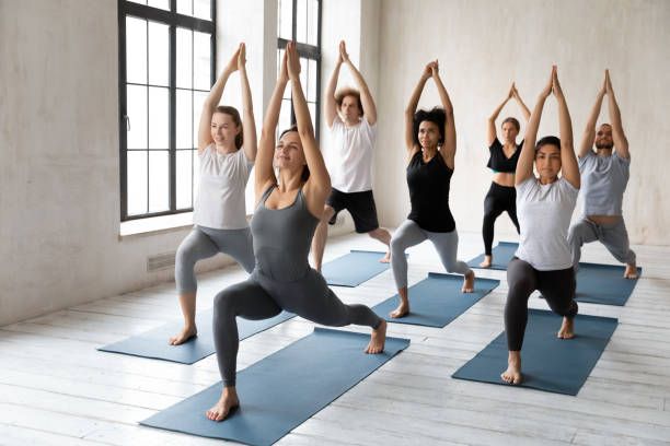 istock Diverse people practising asana with coach doing Warrior one asana 1222252749