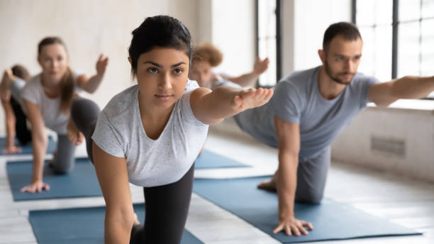 インドのコーチとバードドッグポーズをしている人々のグループ - yoga class instructor yoga exercising ストックフォトと画像