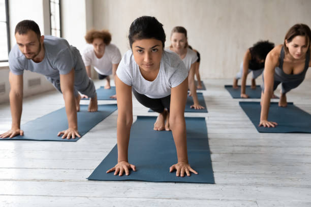 istock Group of people and indian instructor standing in Plank pose 1222252768