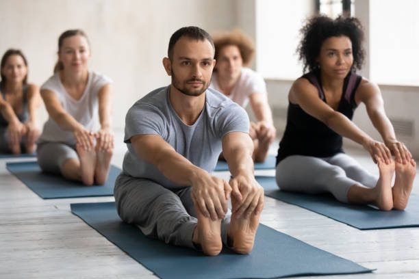 istock Male with group of diverse people practicing Seated Forward Bend 1222252776