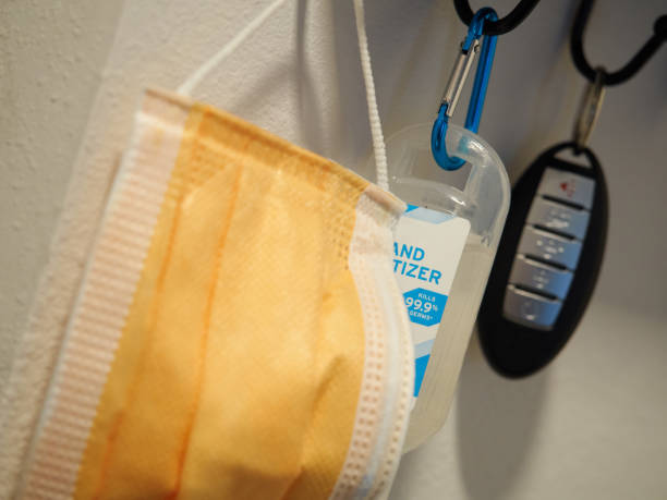 Mask with hand sanitizer and car key hanging on key rack selective focus stock photo