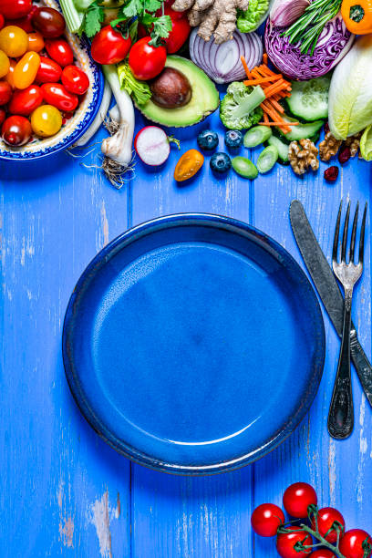 ビーガン料理:空の青いプレートと健康的な新鮮な野菜の境界線。スペースをコピーする - ingredient broccoli cherry tomato carrot ストックフォトと画像