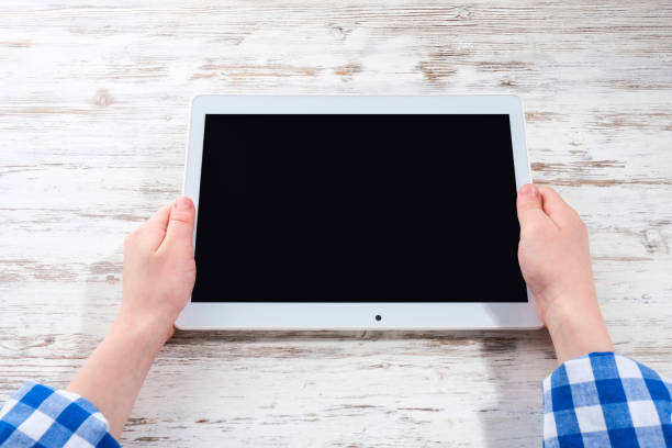 istock Hands with a tablet on the table. The girl holds a tablet in her hands. 1222257403