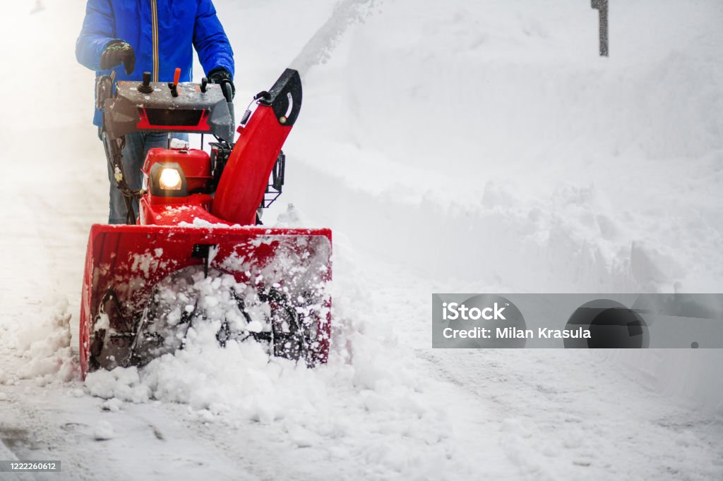 Man clearing or removing snow with a snowblower Man clearing or removing snow with a snowblower on a snowy road detail. Snow Stock Photo