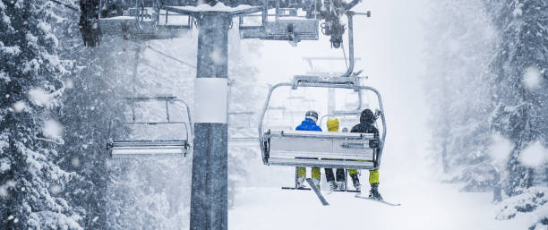istock Three skiers on ski lift in heavy snowing storm. 1222260660