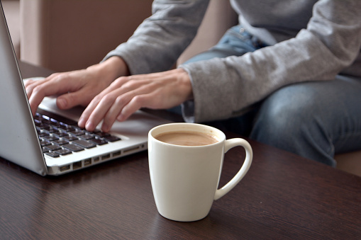 Online work or home education concept. Hand of a young female freelancer working on a laptop from a home office