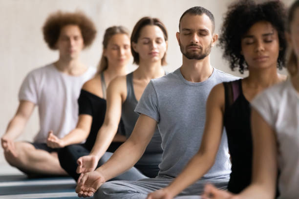 grupo de diversas personas meditando visualizando durante la sesión de yoga - aspirations what vacations sport fotografías e imágenes de stock