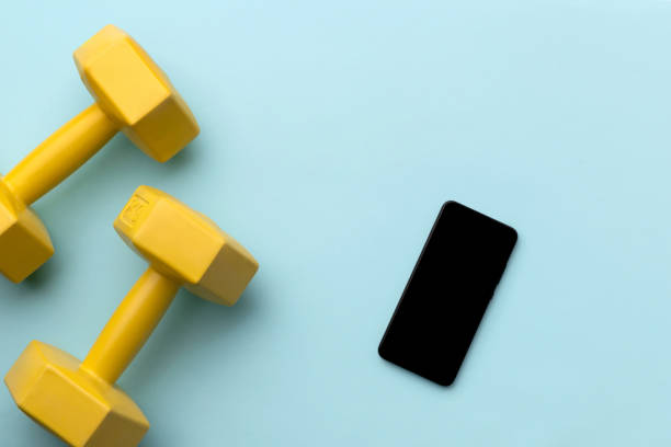 istock Flat lay top view yellow dumbbells and smartphone on blue background 1222265503