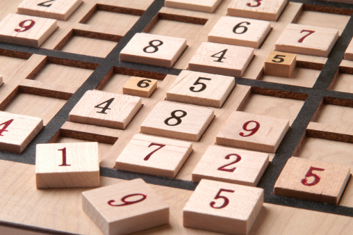 Close up of a wood Sudoku Game Board with puzzle in progress.