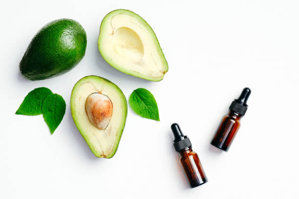 istock Essential oils bottles and avocado with green leaves on white background. Flat lay, top view. Aromatherapy massage oil, avocado treatment concept 1222266837