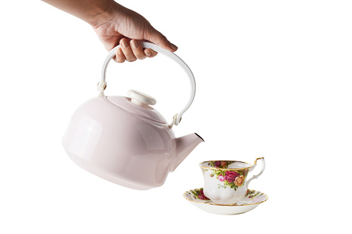 Woman hand holding ceramic teapot and her hand filling the tea (Clipping Path)