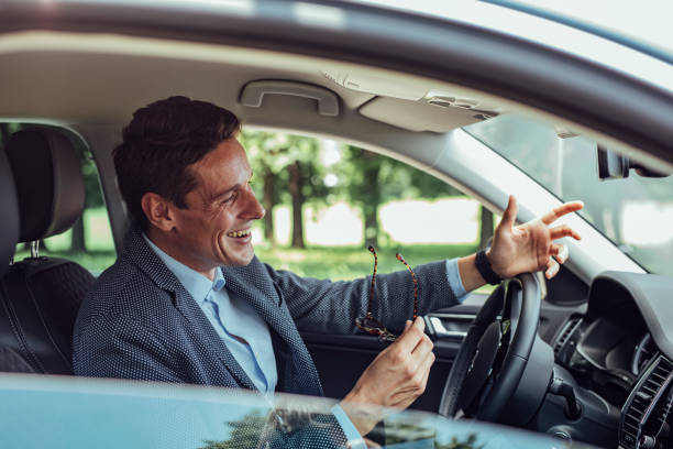 feliz hombre de negocios durante una conversación manos libres en su coche - mobile phone telephone bluetooth men fotografías e imágenes de stock