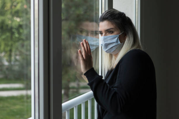 istock woman with face mask looking outside 1222273179