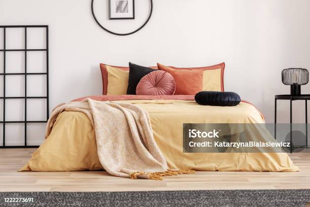 Black Round Velvet Pillow On Yellow Duvet In Trendy Bedroom Interior With King Size Bed Stock Photo - Download Image Now