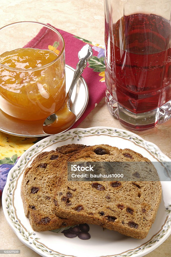 Toast & Jam--Spelt with Raisins Close up of freshly-baked and toasted organic spelt with raisins bread with orange marmalade preserves and cranberry juice. Bread Stock Photo