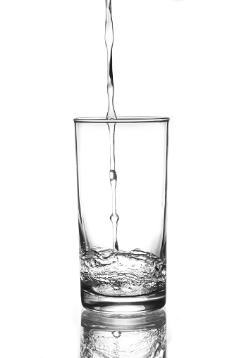 A glass of water. Water falling into the glass.
