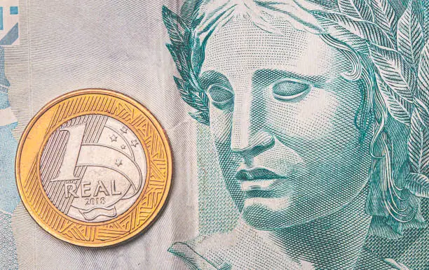 Real - Brazilian Currency. Money, Dinheiro, Brasil, Brazil, Reais. A Real coin on a brazilian banknote in close-up.