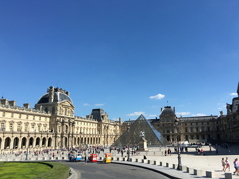 Paris, France - September 9, 2016: The Lourve is visited by thousands of tourists every year and you can see some of them roaming the grounds in this photo. This is one of the most popular tourist destinations in France displayed over 60,000 square meters of exhibition space.