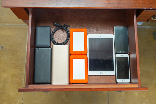 Hard drives, chargers, tablet, smart phones neatly organized in a drawer.