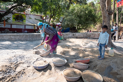 Candolim, India - February 6th, 2020: Unidentified woman prepares sand for building construction in Candolim, Goa, India. Hard manual work for women are still widely used in India.