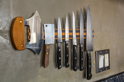 Kitchen knives on a magnet on a wall.