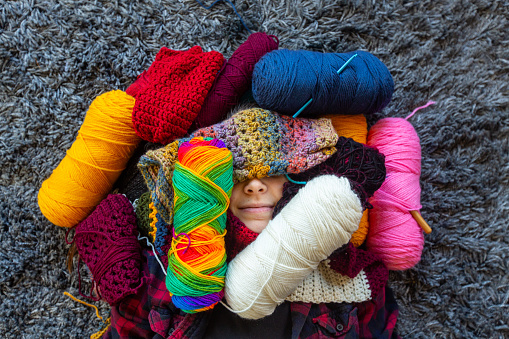 High angle view of woman's face covered in yarn