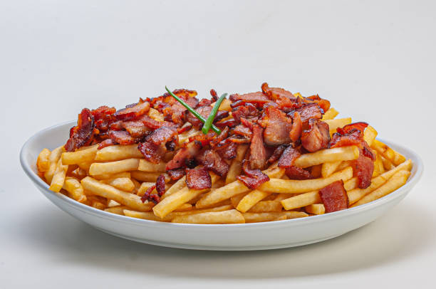 Portion of french fries with sliced bacon Pork chips with sliced bacon. served as input. Highly caloric and greasy appetizer. 
It can be accompanied with pepper sauces, various types of breads and herb mayonnaise, mustards among others. 
It's a calorie-high product. Harmonizes with various types of craft beers fried potato stock pictures, royalty-free photos & images