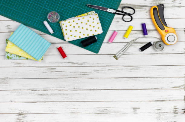 istock quilting, embroidery and sewing tools on the white wooden background. patchwork knife, scissors, lined cutting mat, self-locking, threads, measuring tape, floss, hoop. copy space. flat lay 1222282859