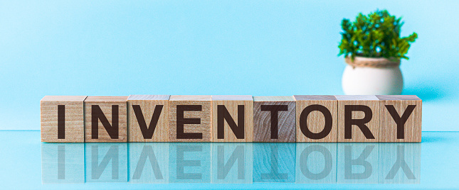 Palabra INVENTORY hecha con bloques de madera en un fondo azul photo