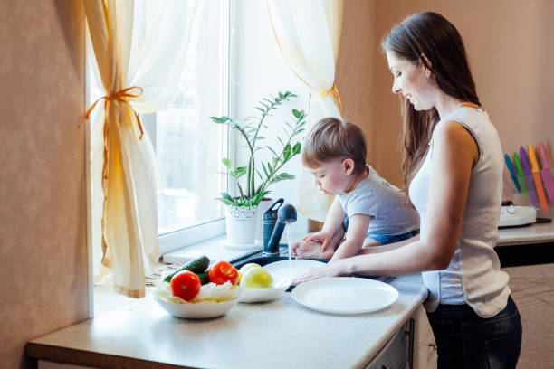 キッチンママの息子は果物や野菜を洗う - minute maid beverages ストックフォトと画像