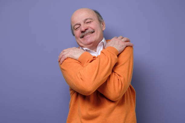 istock senior man hugs himself, has high self esteem feeling happy being alone. 1222286037